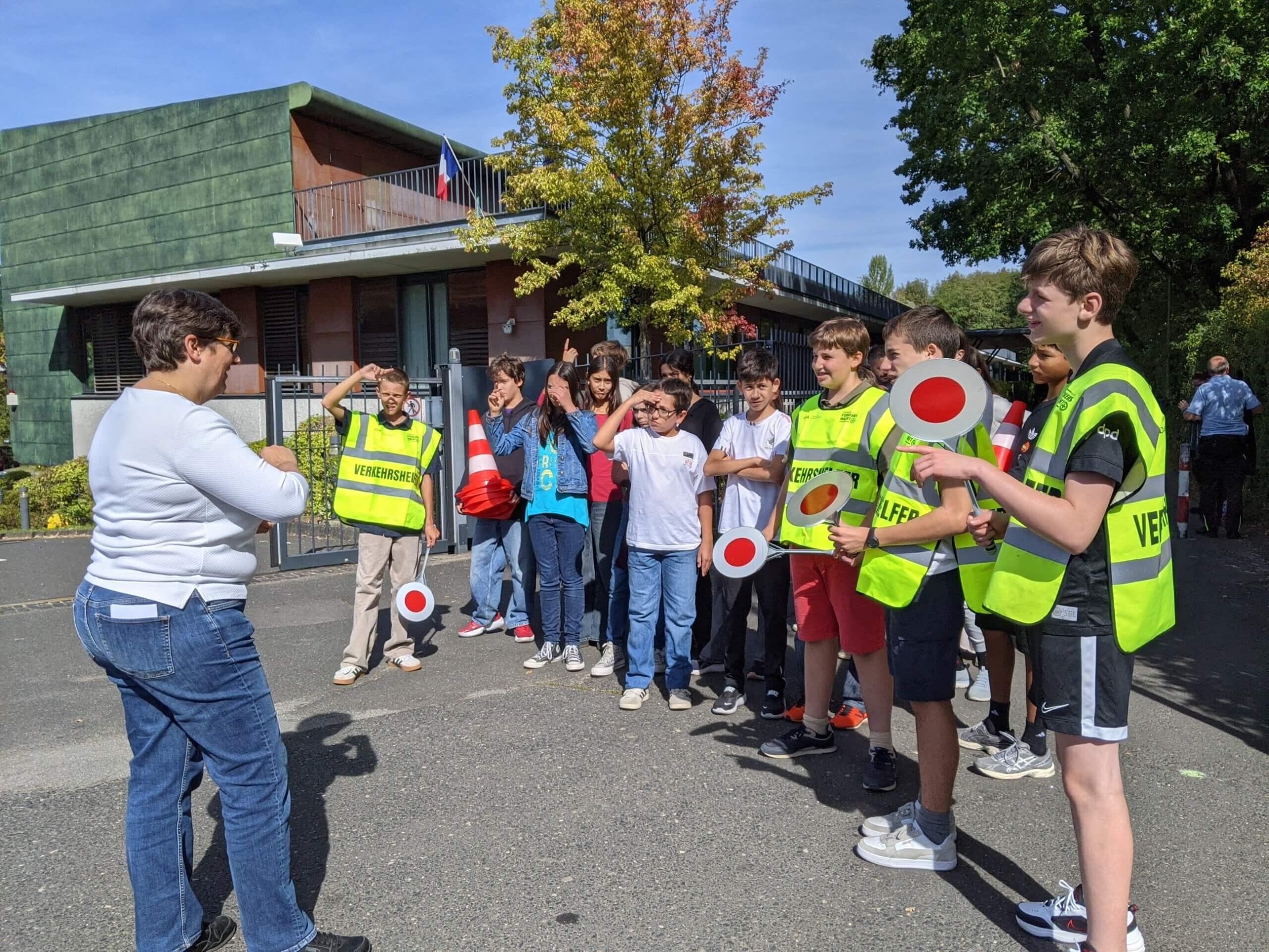 Elèves devant l'école française internationale Victor Hugo à Francfort sur le Main qui sont formés à la gestion de la circulation des voitures sur le parking